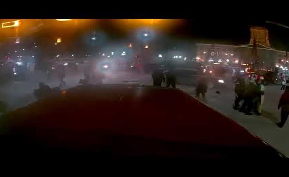 Une image nocturne filmée à travers un pare-brise montre des manifestants, des policiers et des feux de véhicules au moment de l’incident de Winnipeg. Capture d’une vidéo témoin reprise dans les médias.