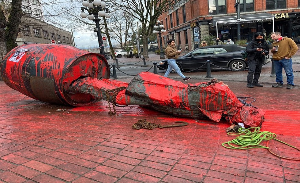 La statue de Gassy Jack repose sur la chaussée de briques, couverte de peinture rouge et entourée de cordes après son déboulonnement. Photo : Jen St. Denis / The Tyee.