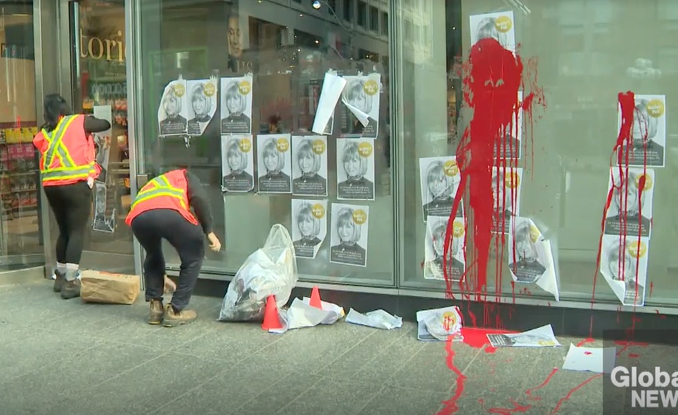 La façade du magasin Indigo de Toronto est couverte de peinture rouge et d’affiches représentant Heather Reisman, tandis que des employés commencent le nettoyage. Photo : Friends of Simon Wiesenthal Center / CityNews.