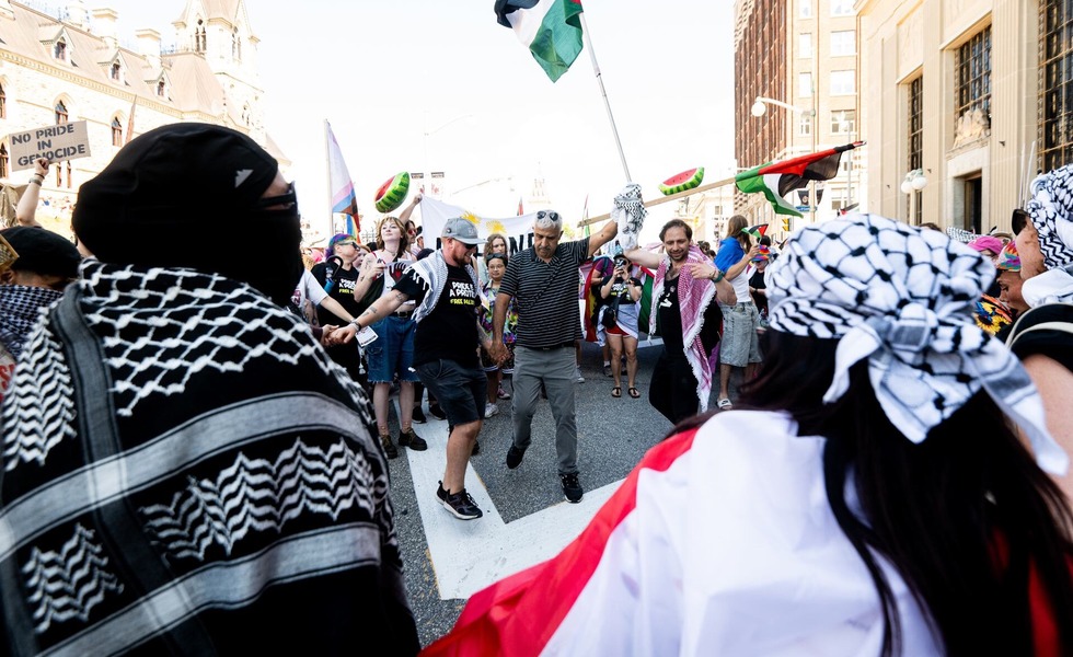 Des militants de Queers for Palestine, portant des keffiehs et des drapeaux palestiniens, bloquent le parcours du défilé Capital Pride à Ottawa. Photo : Spencer Colby / La Presse canadienne.
