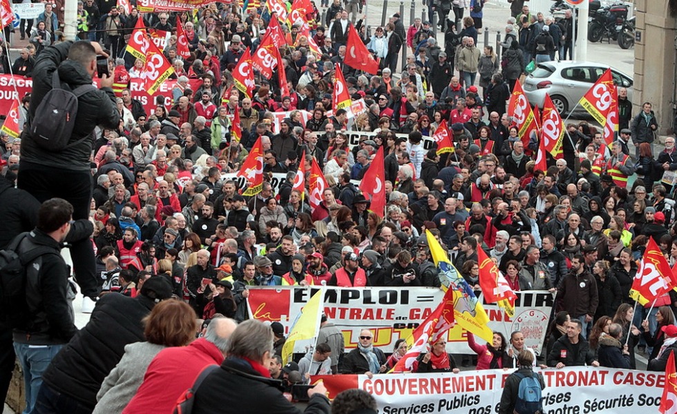 Une foule dense de manifestants, entourée de drapeaux syndicaux et de banderoles, remplit une avenue parisienne lors du défilé du 1er mai 2021.