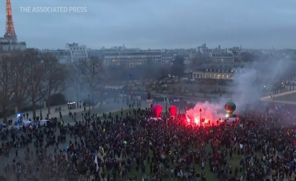 Une vaste foule se rassemble près de la tour Eiffel, tandis que des fumigènes rouges et de la fumée marquent la manifestation contre la réforme des retraites du 31 janvier 2023.