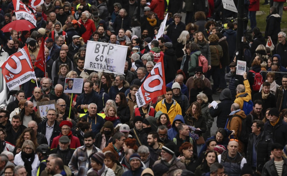 Des manifestants et des drapeaux syndicaux remplissent le cortège parisien du 11 mars 2023; une pancarte réclame la retraite à 60 ans dans le secteur du bâtiment.