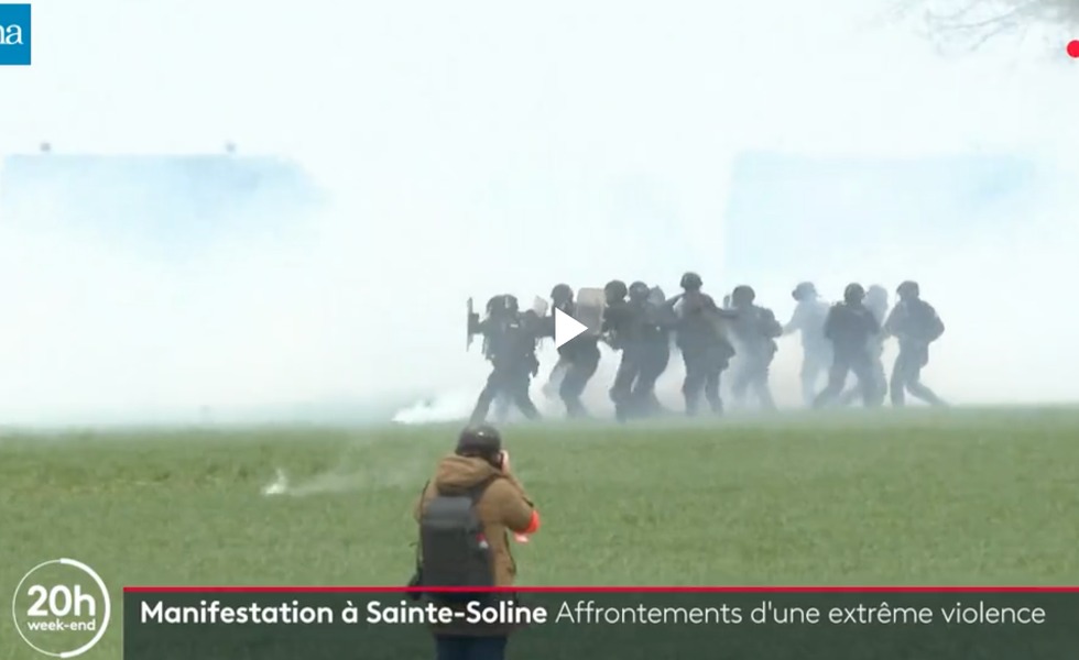 Des gendarmes progressent en formation dans un champ couvert de gaz lacrymogène pendant les affrontements de Sainte-Soline, le 25 mars 2023.