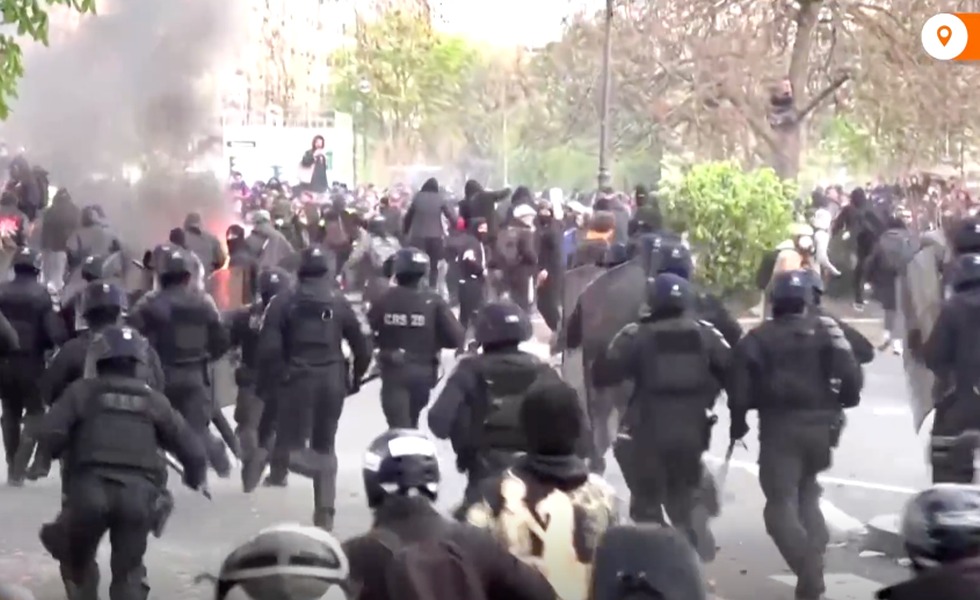Un important dispositif de policiers antiémeute charge dans une rue parisienne enfumée pendant la mobilisation contre les retraites du 28 mars 2023.