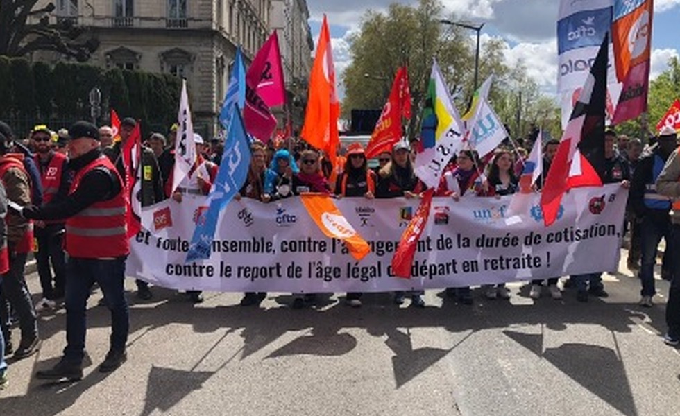 Des manifestants défilent derrière une banderole syndicale et de nombreux drapeaux lors de la mobilisation parisienne du 13 avril 2023.