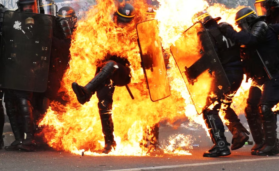 Des policiers portent secours à un collègue dont les vêtements sont en flammes après le lancement d’un engin incendiaire pendant le défilé du 1er mai 2023 à Paris.