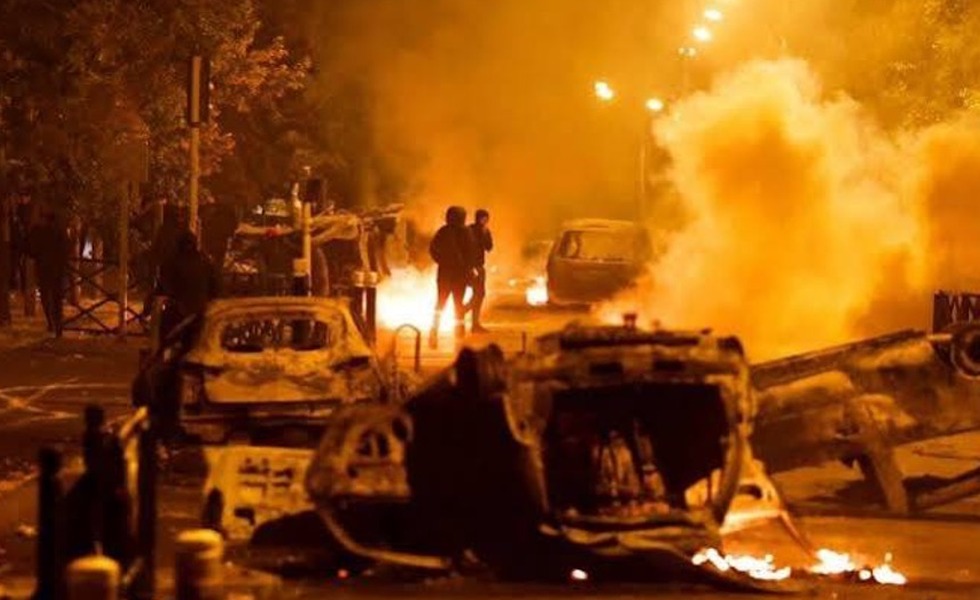 Des véhicules renversés et calcinés brûlent dans une rue, sous un épais nuage de fumée, pendant les émeutes qui ont suivi la mort de Nahel.