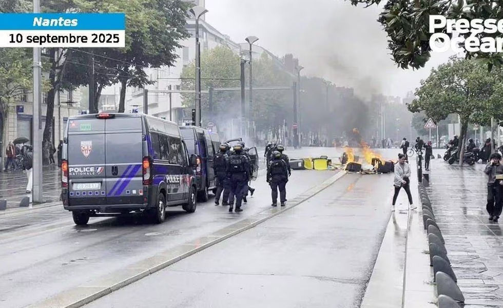 À Nantes, un fourgon et des policiers antiémeute avancent vers des barricades fumantes, tandis que des manifestants se dispersent au loin.
