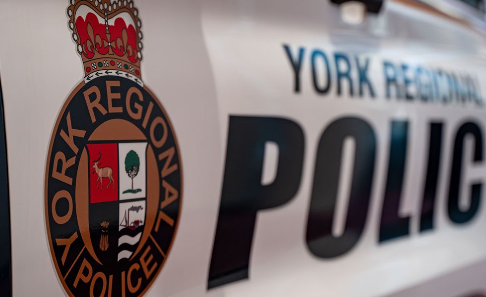 Gros plan sur l’écusson de la police régionale de York apposé sur le flanc d’un véhicule de police blanc, avec l’inscription « York Regional Police » floue à l’arrière-plan.