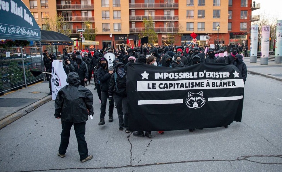 Le cortège anticapitaliste progresse près du marché Atwater derrière une bannière noire portant le message « Impossible d’exister, le capitalisme à blâmer ». Photo : Thierry Laforce / Agence QMI, publiée par Le Journal de Montréal et TVA Nouvelles.