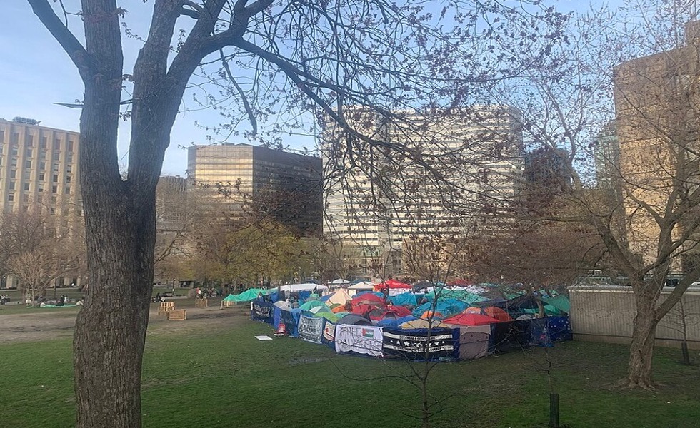 Des tentes, des bâches et des drapeaux composent le campement pro-palestinien installé sur le terrain inférieur de McGill, vu depuis la bibliothèque Redpath. Photo : WikiFouf / Wikimedia Commons, CC0.