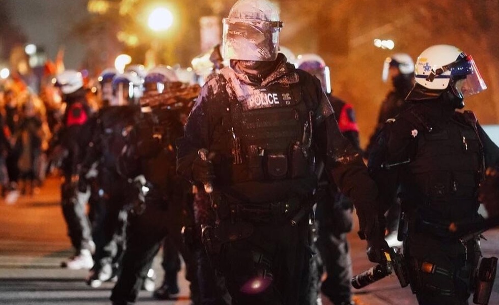Une ligne de policiers antiémeute casqués fait face à des manifestants réunis de nuit lors de la mobilisation contre l’Assemblée parlementaire de l’OTAN. Photo : Mario Beauregard / Agence QMI.