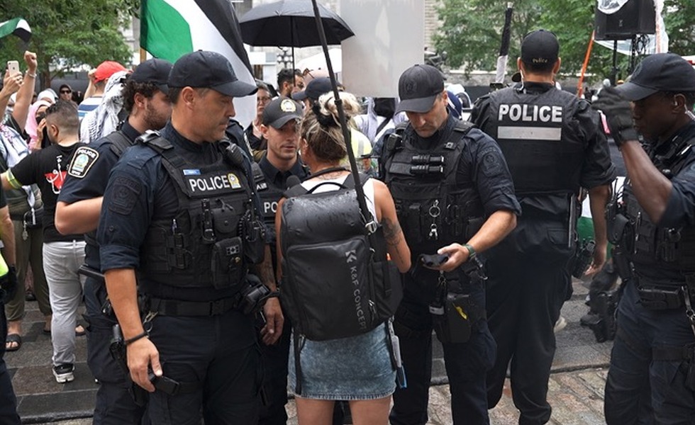 Des policiers et des participants se tiennent autour d’un rassemblement de prière publique, filmé en plein jour par Rebel News. Capture du reportage de Rebel News / YouTube.
