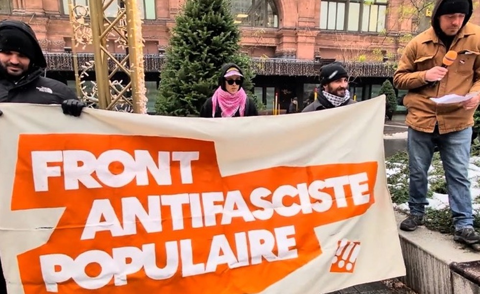 Des participants tiennent une bannière orange et blanche du « Front antifasciste populaire » lors du rassemblement du 23 novembre 2025. Capture du reportage de Rebel News / YouTube.