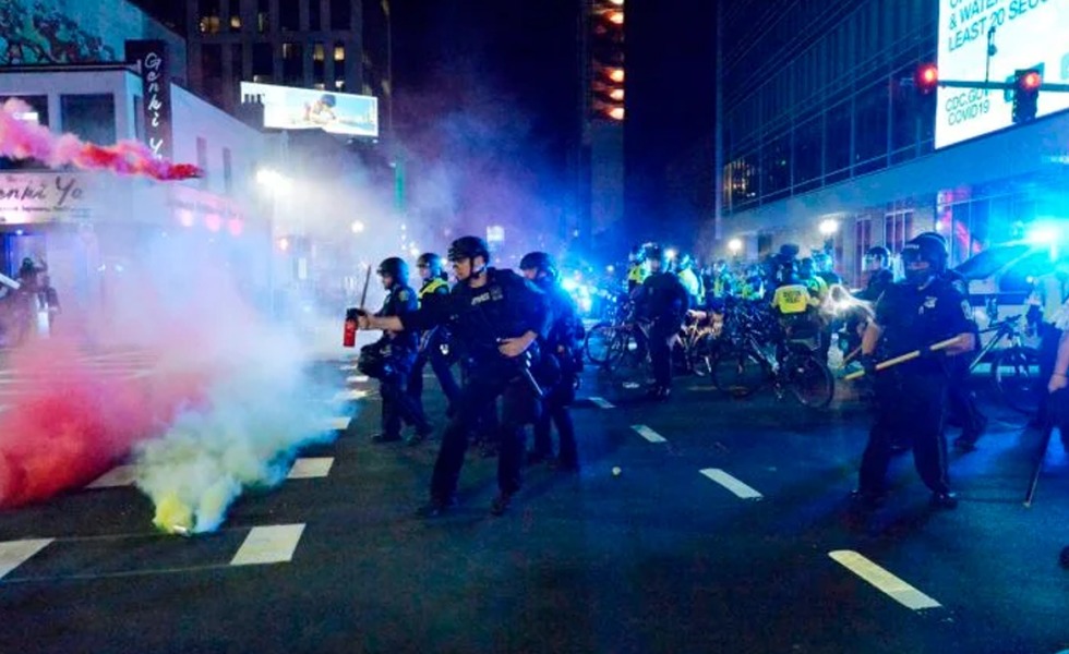 Des policiers avancent dans une rue de Boston envahie par des fumées colorées pendant les troubles du 1er juin 2020.