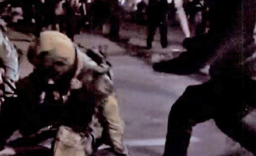 Capture vidéo d’une confrontation nocturne à Portland : un agent est au sol tandis qu’une personne masquée tient une batte.