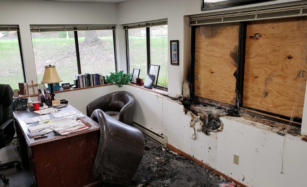 Une pièce de Wisconsin Family Action présente une fenêtre barricadée, des murs noircis et un plancher endommagé après l’incendie.