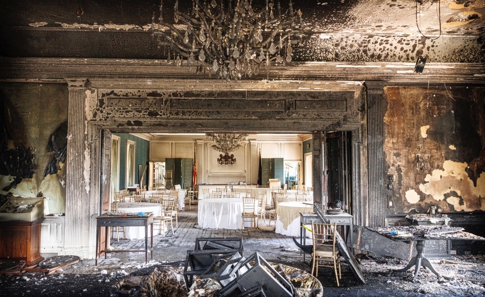 Une pièce de la résidence du gouverneur présente des murs, du mobilier et un lustre lourdement endommagés par l’incendie.